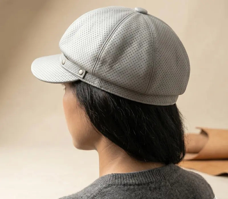 Person wearing a gray cap with a beige background