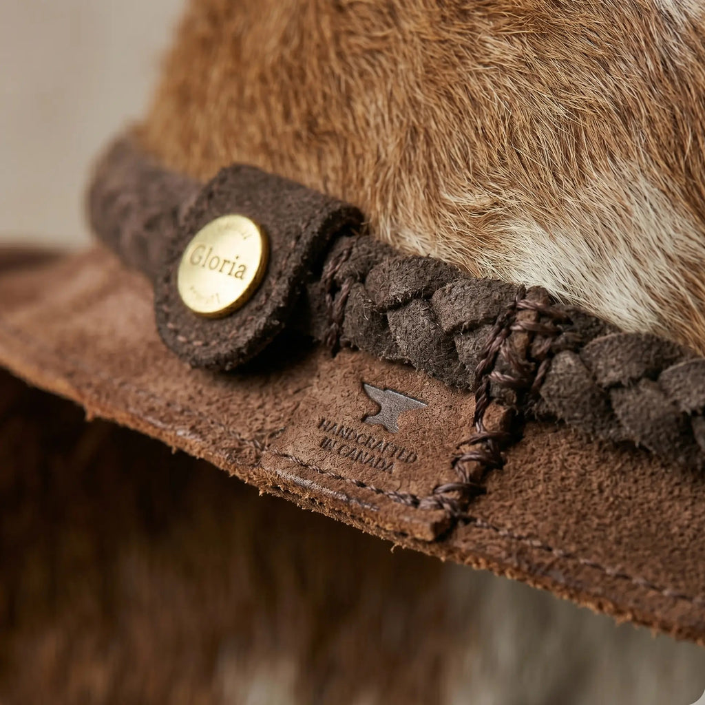 Close-up of a brown fur hat with braided band and 'Gloria' button, brand 'Baker & Taylor' visible.