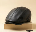 Black leather cap on a beige box with a beige background