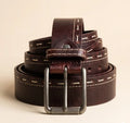 Brown leather belt with silver buckle on a beige background