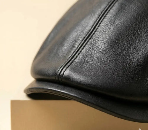 Close-up of a black leather cap on a beige background