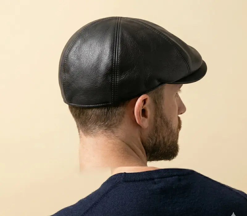 Man wearing a black leather cap against a beige background