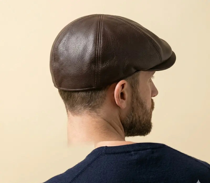 Man wearing a black leather cap against a beige background