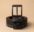 Black leather belt with a buckle on a beige background