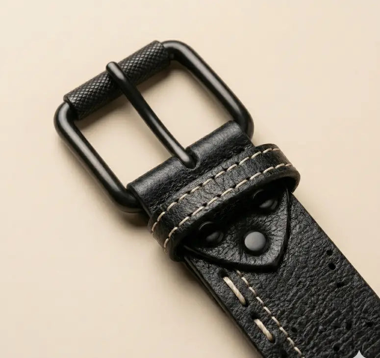 Close-up of a black leather belt with a buckle on a beige background