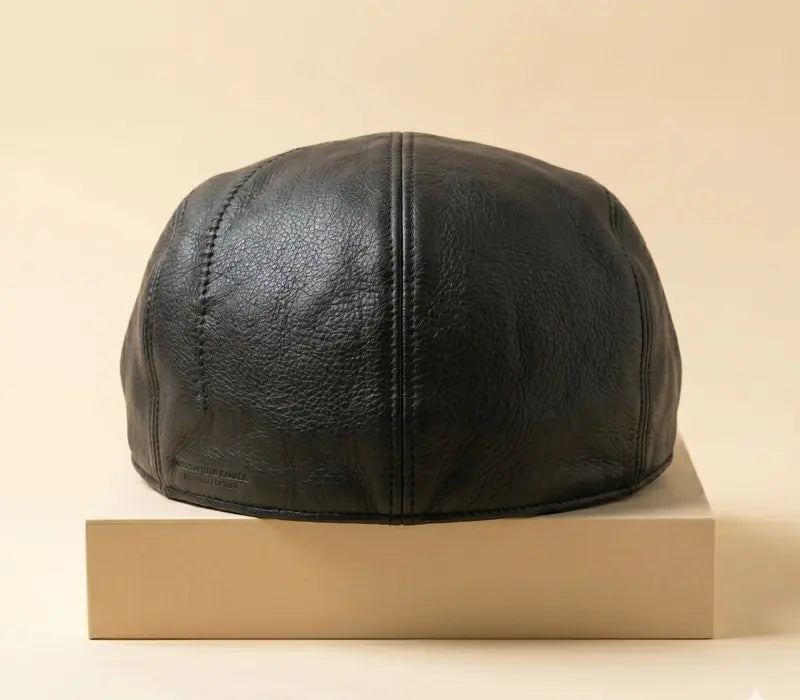 Black leather cap on a beige box against a beige background