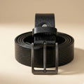 Black leather belt with a silver buckle on a beige background
