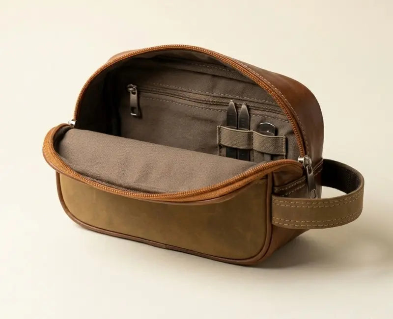 Brown leather toiletry bag with open lid on a beige background