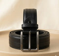 Black leather belt with a silver buckle on a beige surface