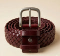 Woven leather belt with a metal buckle on a beige background