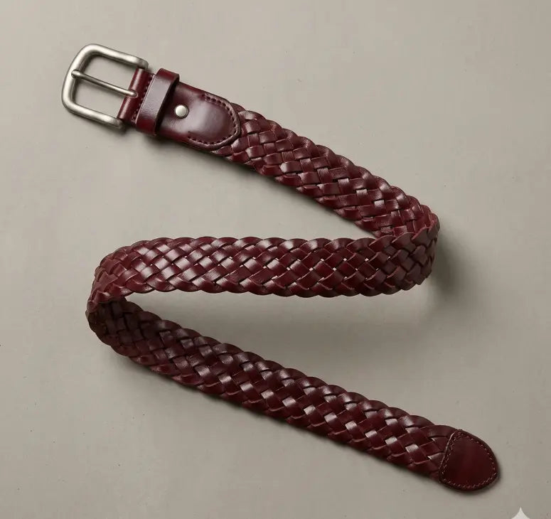 Woven leather belt with a silver buckle on a beige background