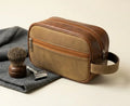 Brown leather toiletry bag with shaving brush and razor on a gray towel