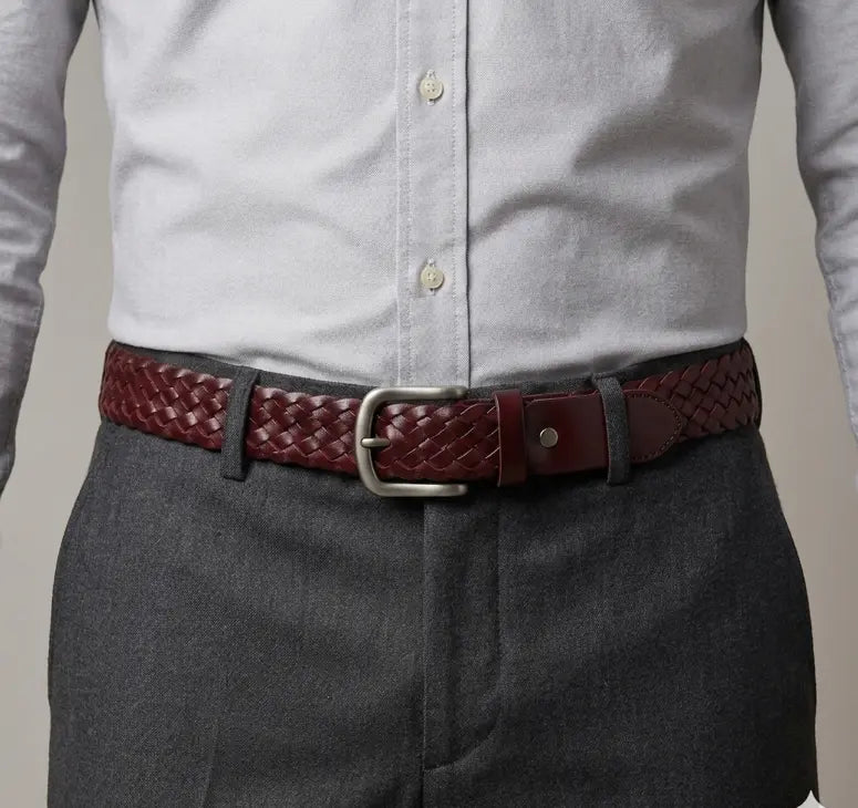 Person wearing a gray shirt and dark pants with a red braided belt.