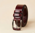 Brown leather belt with silver buckle on a beige background