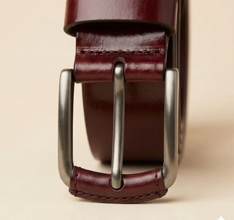 Brown leather belt with a silver buckle on a beige background