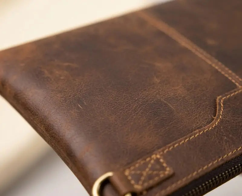 Close-up of a brown leather wallet with visible stitching on a blurred background