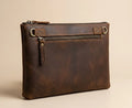 Brown leather clutch bag with a zipper on a beige background